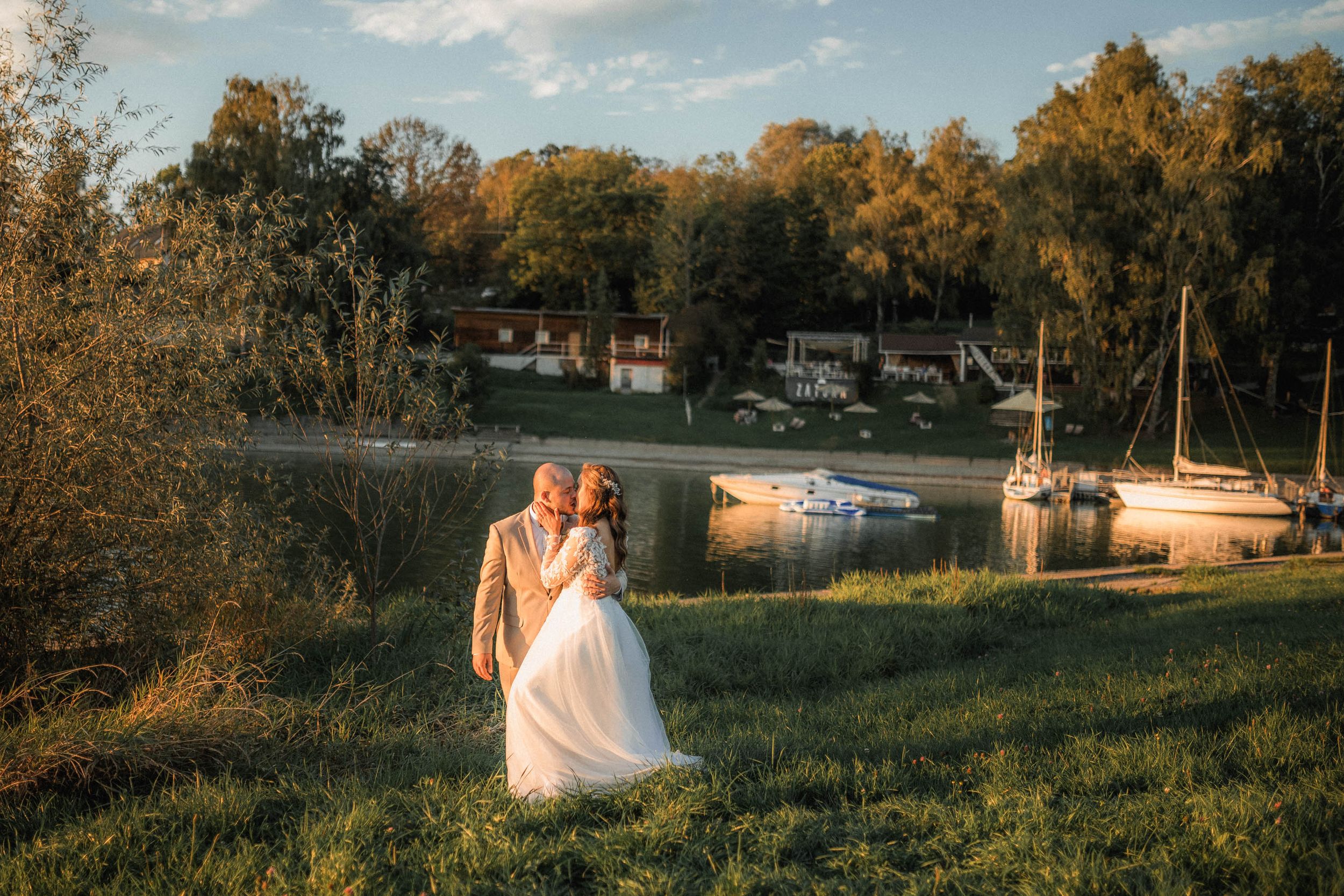 A romantic sunset photoshoot by a lakeside with golden autumn trees in the background.