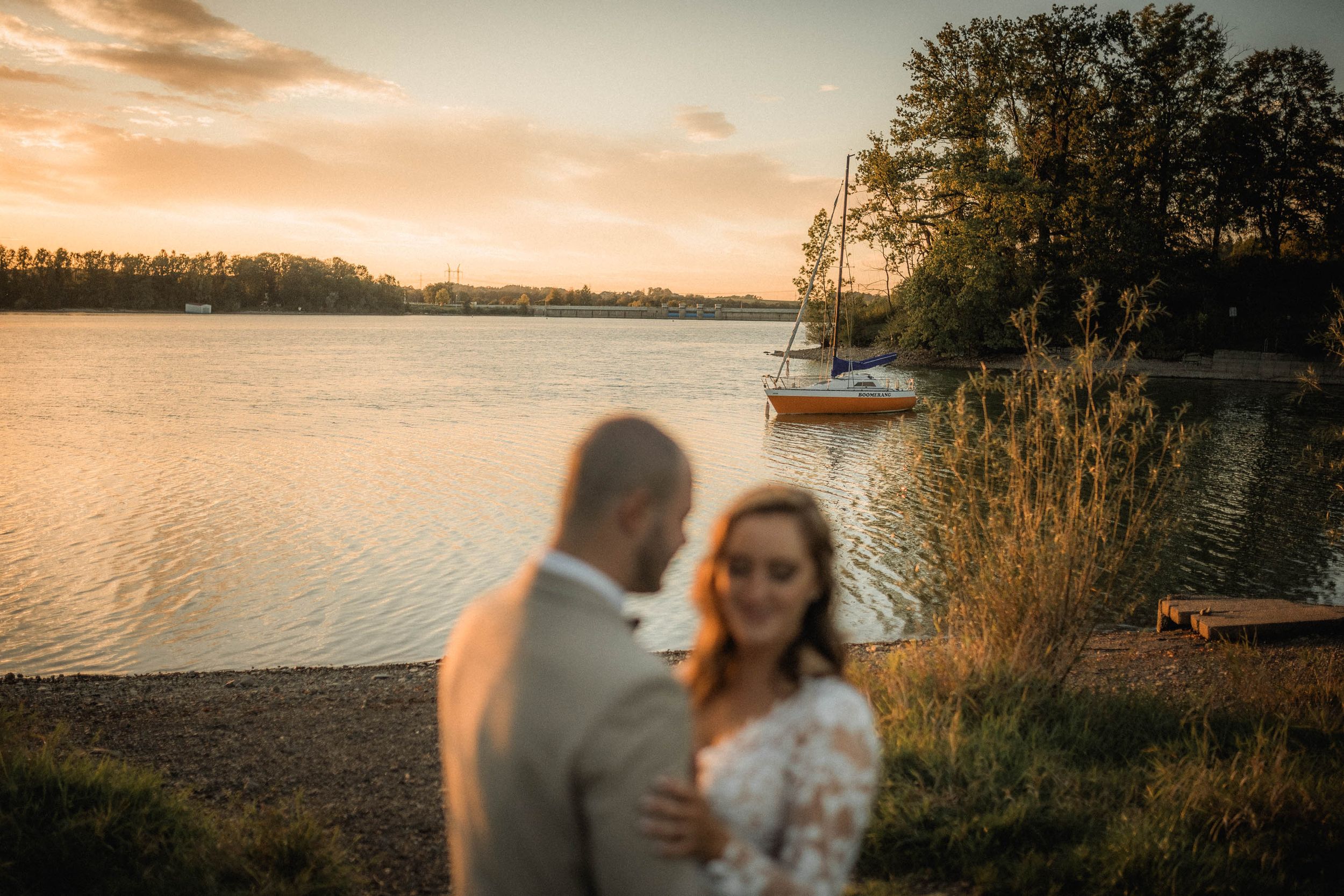 Golden hour wedding photography session with dramatic sunset sky over a lake.