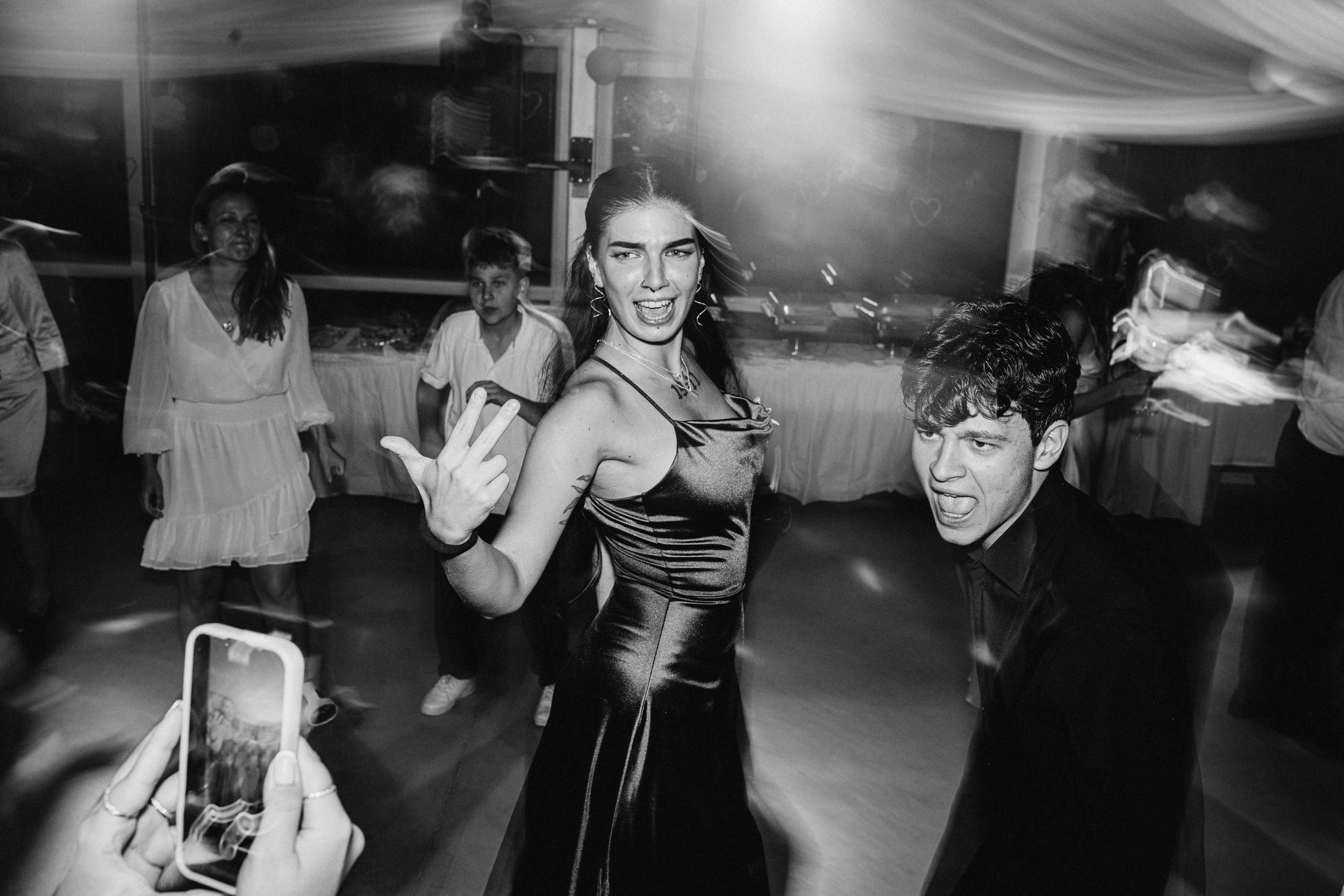 Black and white shot of people dancing and celebrating at a wedding reception.