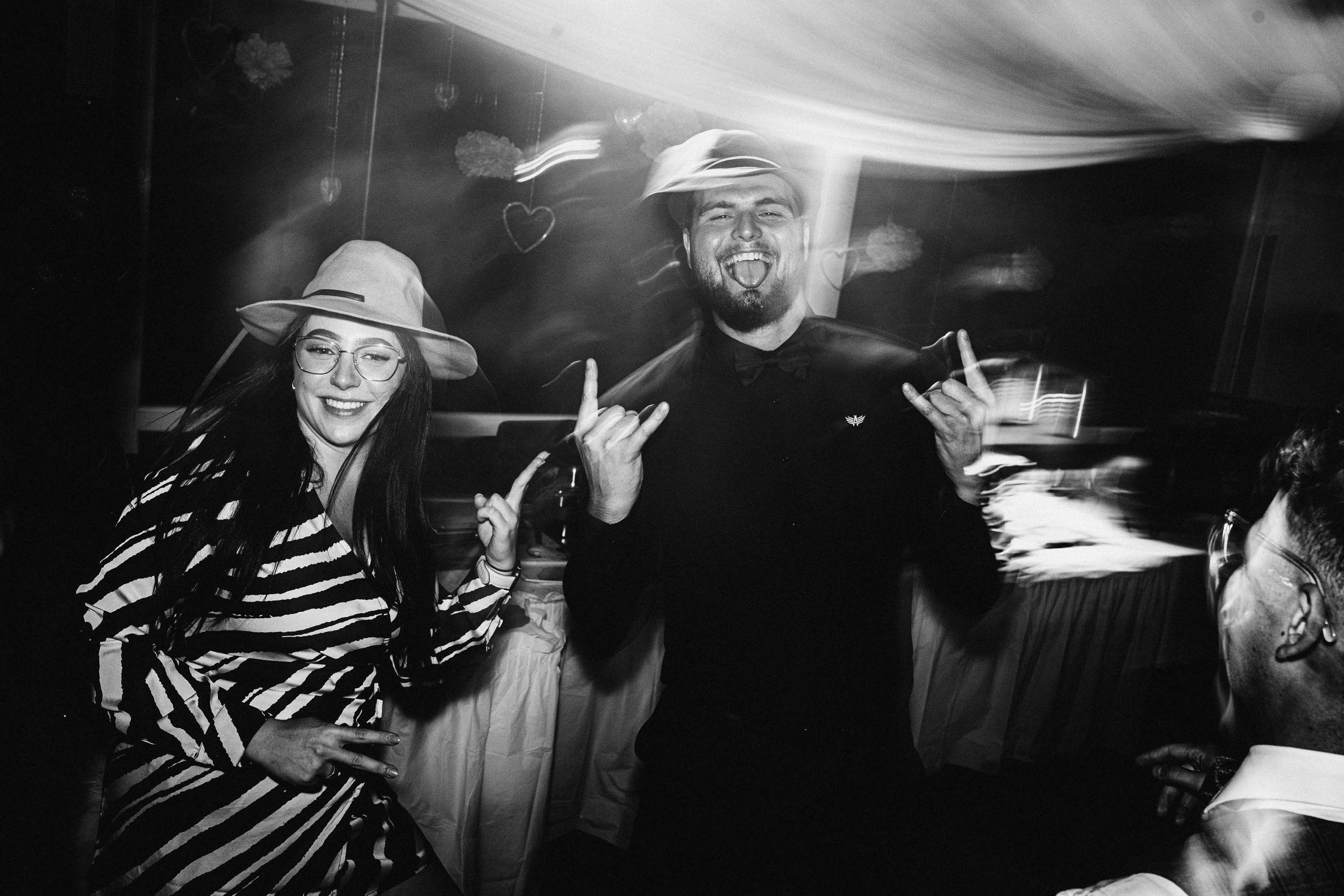 Black and white candid shots of party guests dancing and celebrating at a wedding.