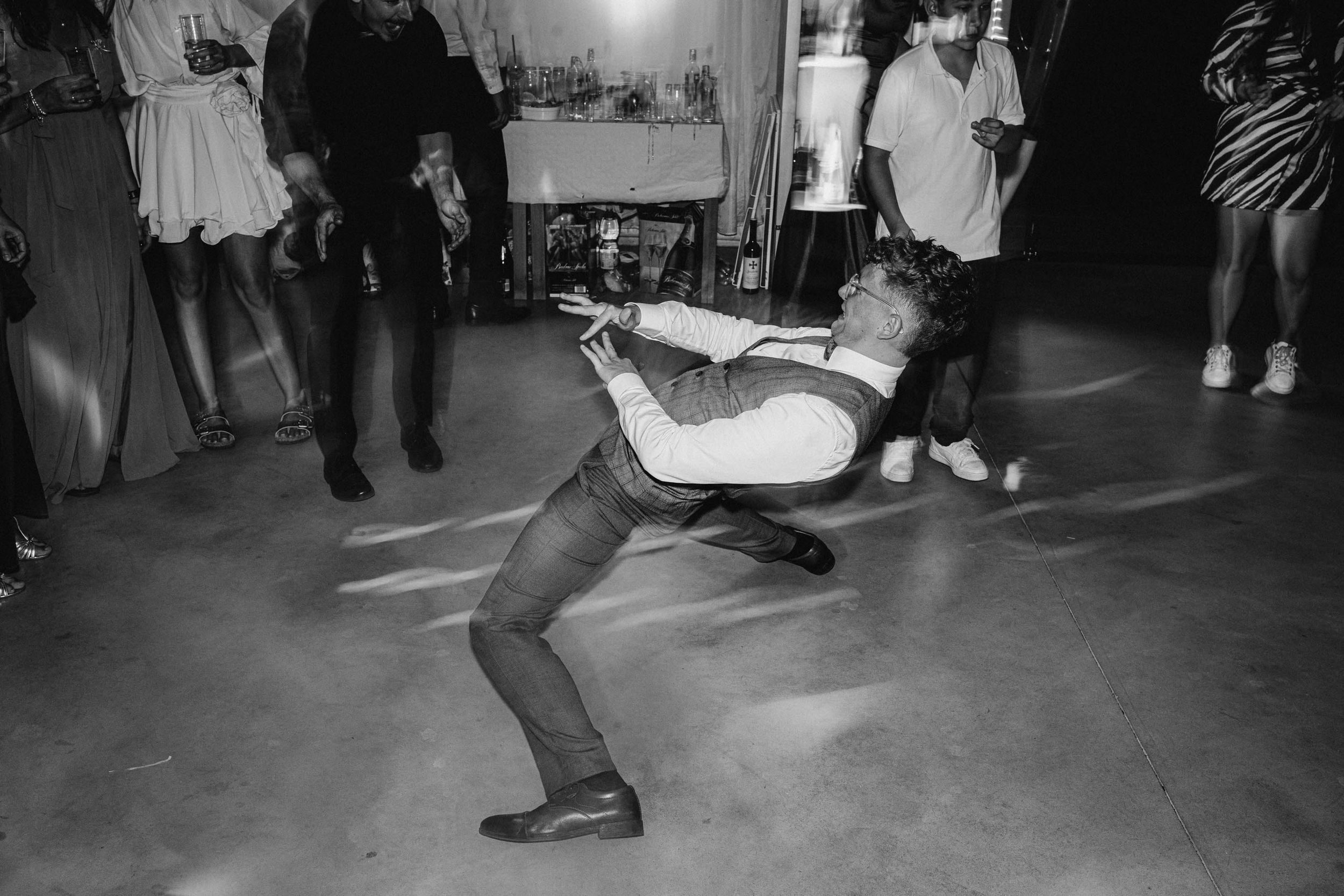 Dynamic dance floor moments captured at a wedding reception with dramatic lighting.