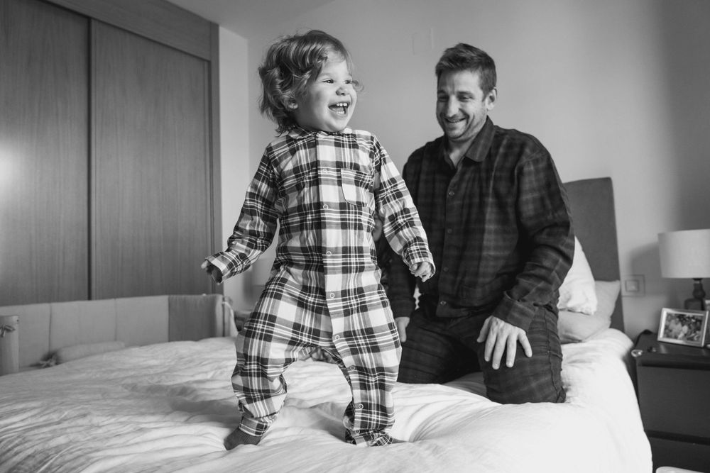 A series of black and white photos showing a couple sitting on a bed in casual plaid clothing.