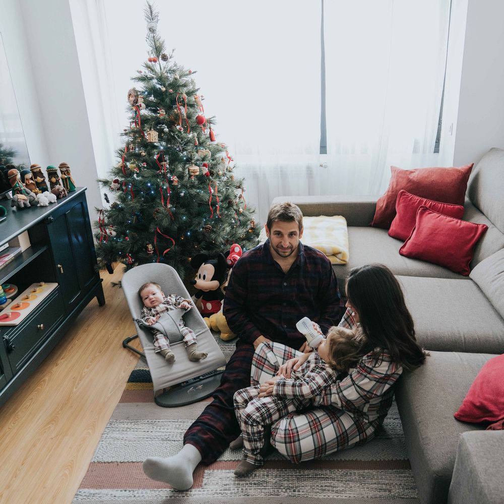 Family spending cozy time together in living room with Christmas tree and decorations during holiday season.