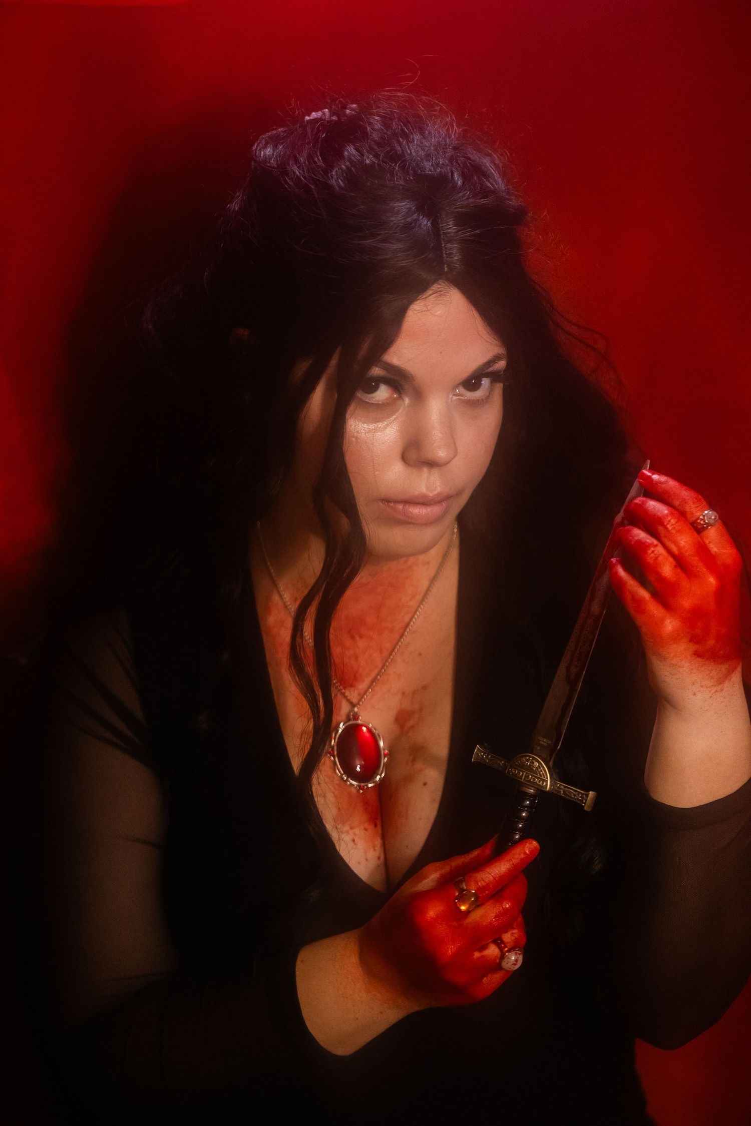 The love witch inspired halloween photoshoot with red lighting shows a figure with long dark hair making dramatic poses.