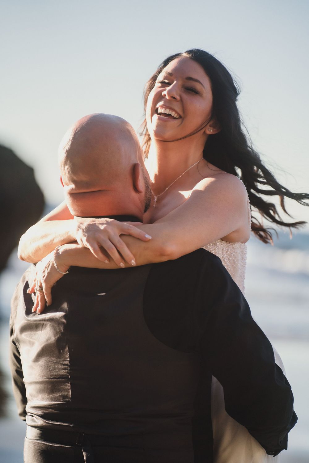 A couple shares joyful embraces and laughter during a sunset photo session.