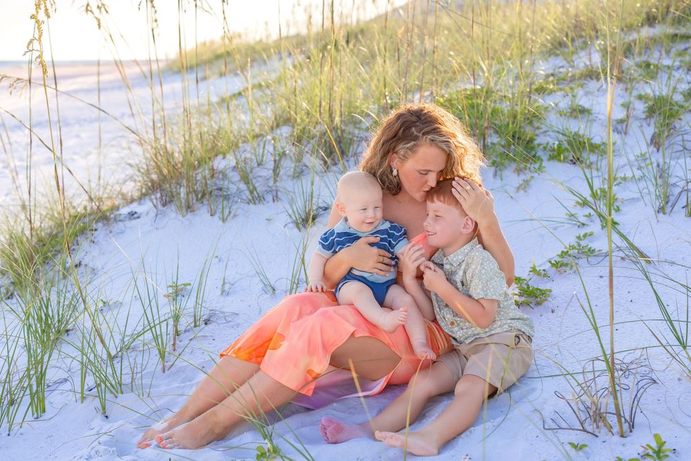 Four people lounging and relaxing on a sandy beach with sea grass during a sunny summer day.