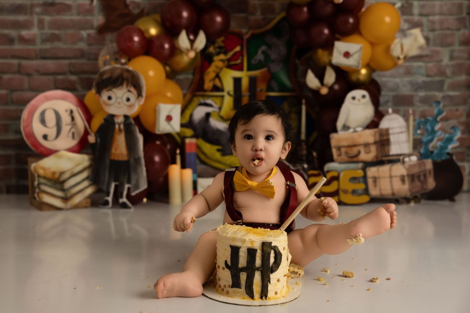 Magical cake smash photo with Harry Potter themed decorations and yellow frosting covered cake.