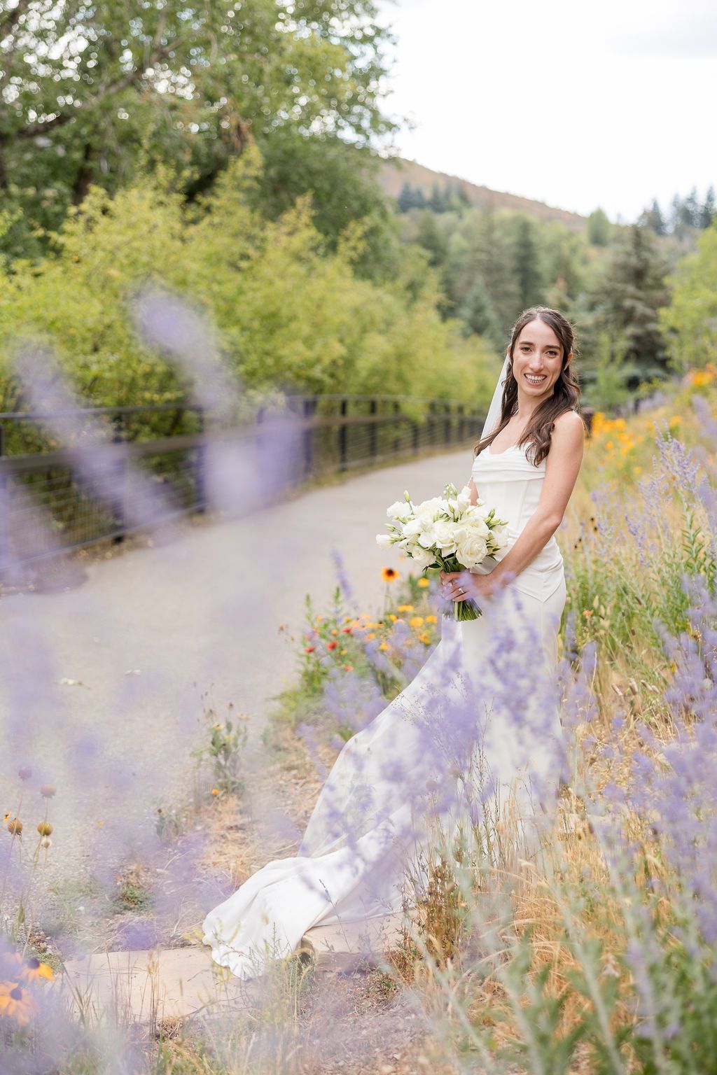 A dreamy bridal portrait session in a wildflower meadow with purple lupines and golden flowers at sunset.