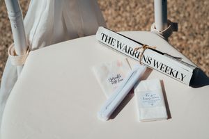 The Warren's Weekly newspaper sits on a cream colored surface next to a white tube and business cards.
