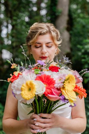 A serene moment in nature with a vibrant bouquet of gerbera daisies, yellow flowers and wildflowers against a forest backdrop.