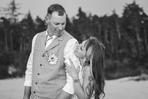 A couple shares a joyful moment outdoors with trees in the background in black and white photography.