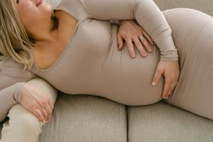 Intimate maternity photo session on cream colored couch showing loving family moment.