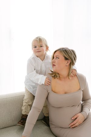 A heartwarming maternity photoshoot showing tender moments between mother and child on a couch.
