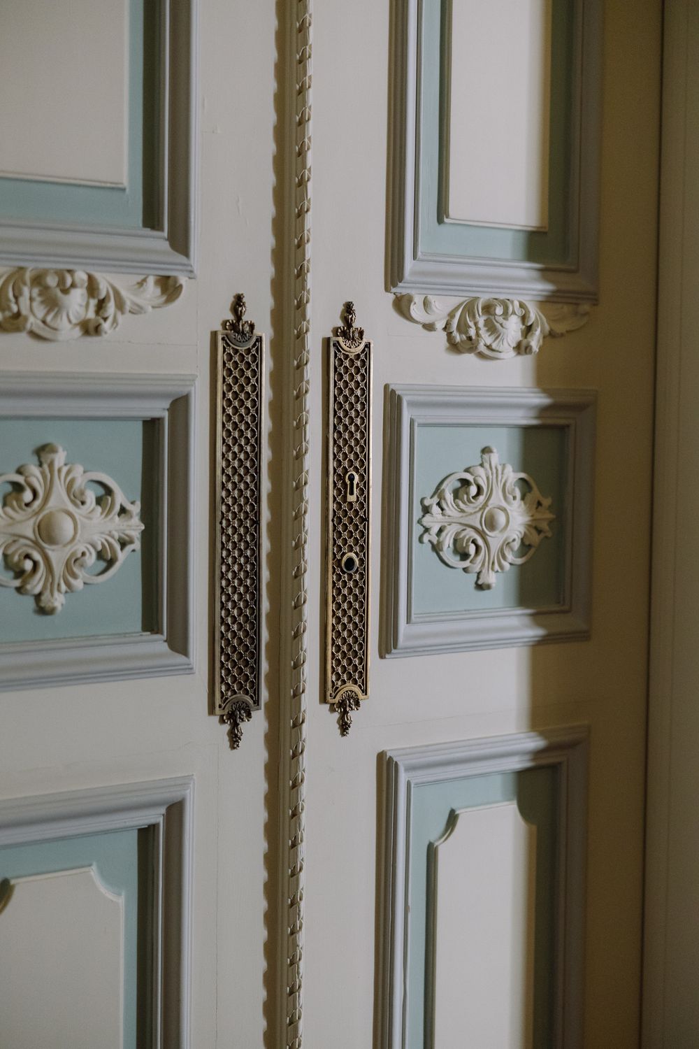 Interior view of ornate white paneled walls with decorative moldings and lattice details in a historic building.