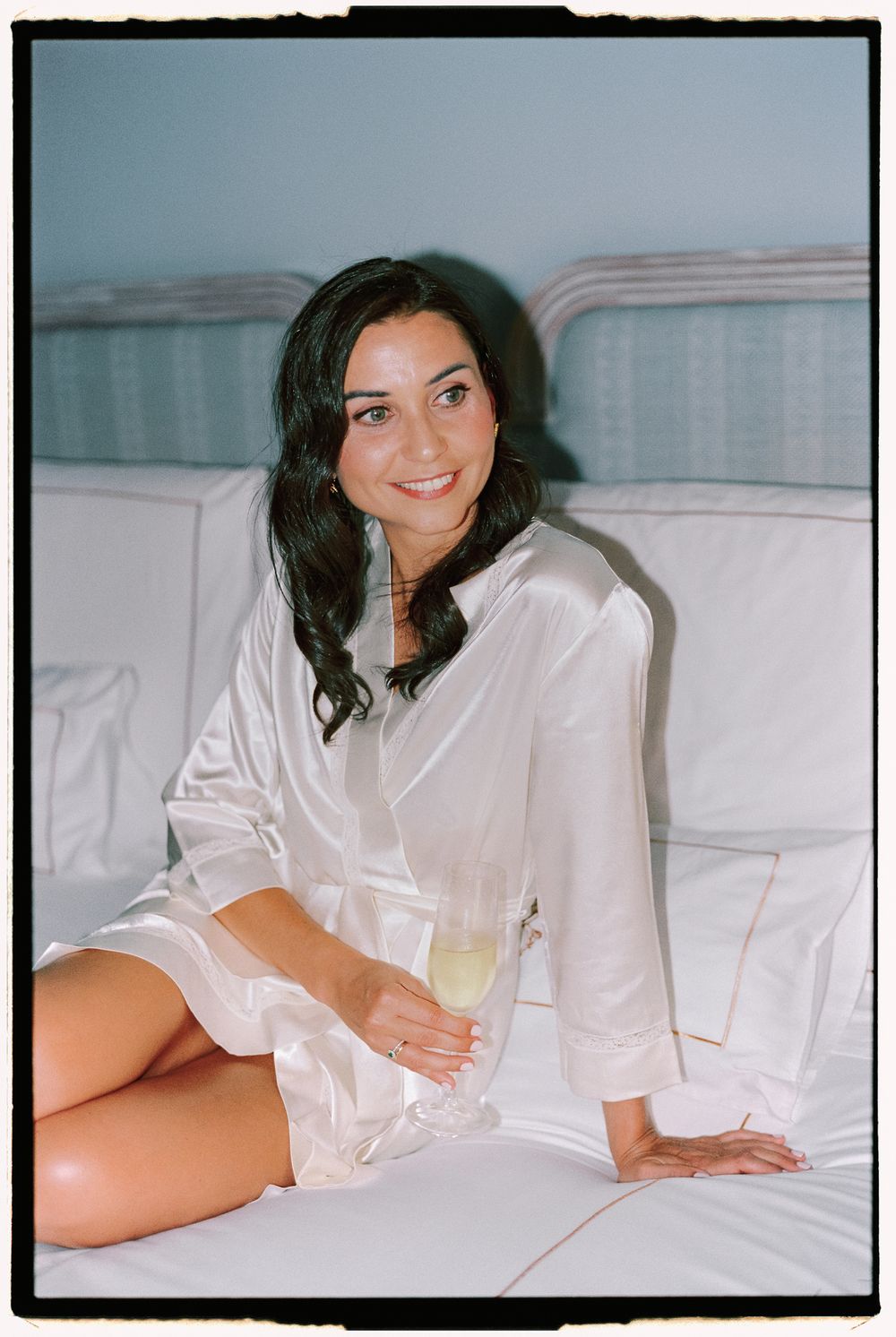 Black and white film-style photos capturing relaxed poses on white bedding in natural morning light.