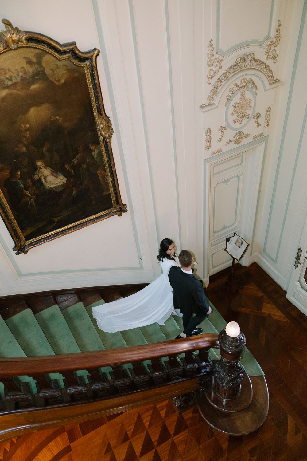 Old baroque staircase with mint green upholstered steps and ornate wall panels in a historic palace interior.