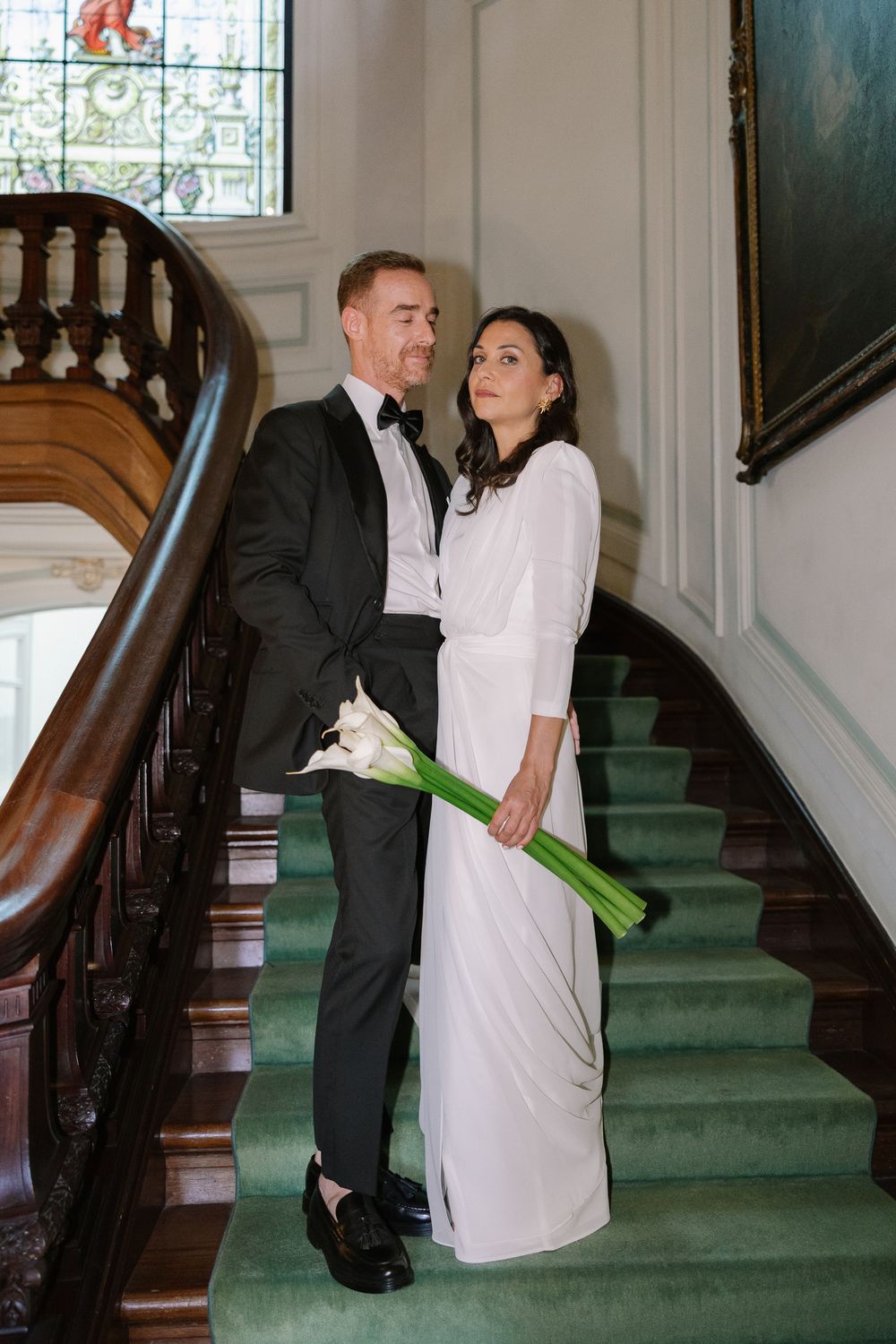 A couple in formal attire shares romantic moments on an elegant staircase in a series of connected photos.