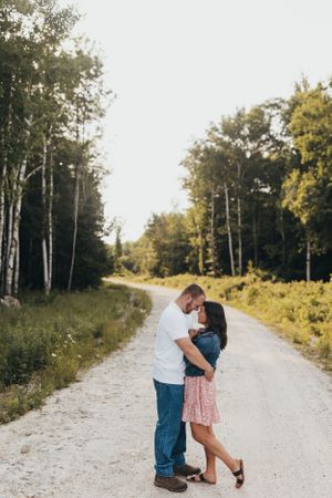 Romantic proposal scene on rural dirt road lined with birch trees.