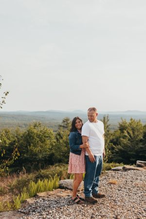 Couple embraces during sunset on rocky mountain overlook.