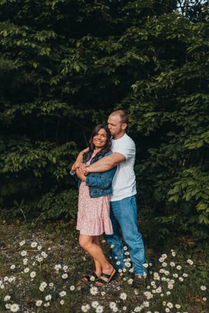 Couple laughs together among blooming wildflowers in nature.