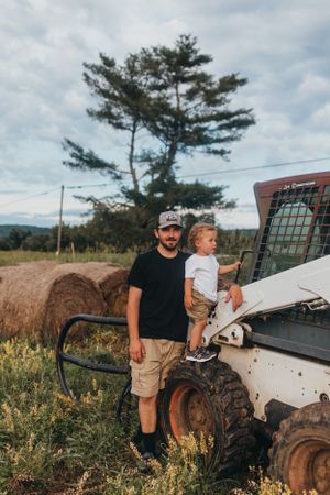 Family exploring around farm equipment in a rural field setting.