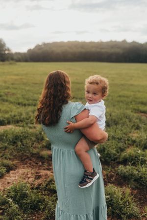 Mother and child sharing tender moments in a sunlit field during golden hour.