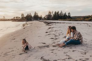 A family enjoying quality time together on a scenic beach with pine trees in the background.