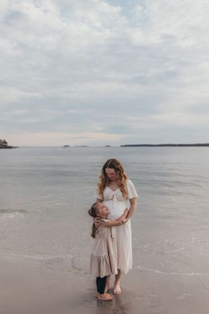 People share a tender moment while standing on the beach near the ocean.