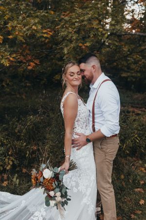 A romantic wedding photoshoot in an autumn forest setting with warm fall colors and natural lighting.