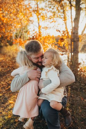 A joyful autumn family moment captured among golden fall foliage.