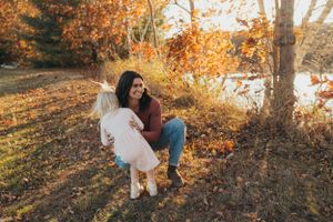 A playful family moment photographed against a backdrop of autumn trees.