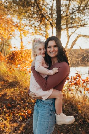 Sweet autumn family moments photographed in warm sunlight with trees showing vibrant fall colors.