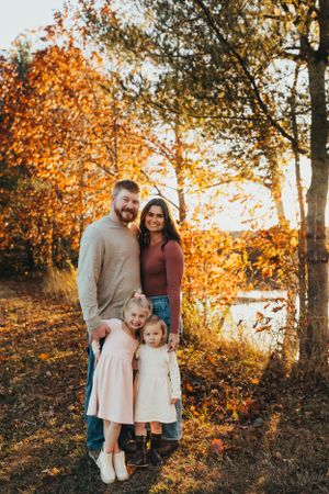 Family portrait session in autumn with beautiful golden sunlight filtering through fall foliage.