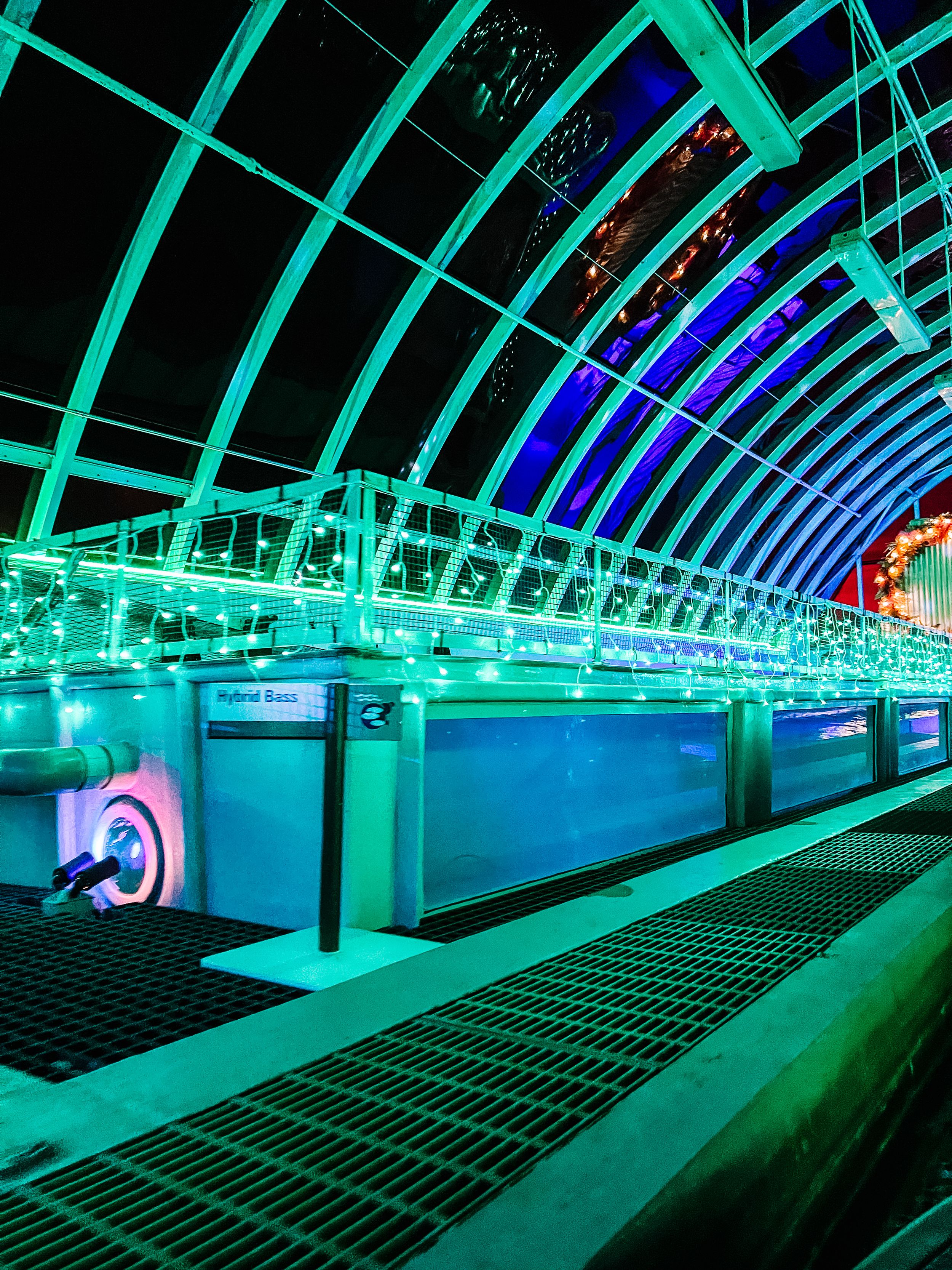 A futuristic tunnel illuminated with vibrant turquoise and blue LED lights creating a mesmerizing architectural perspective.
