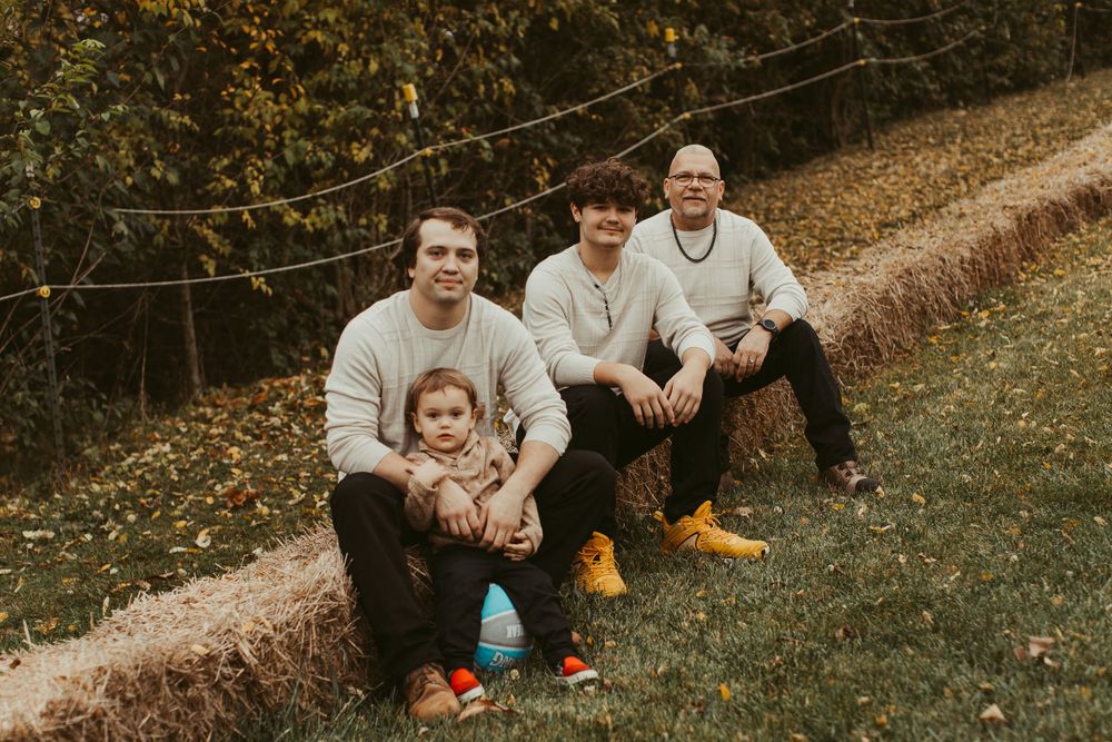 Family members sit casually on grass during an outdoor autumn photoshoot.