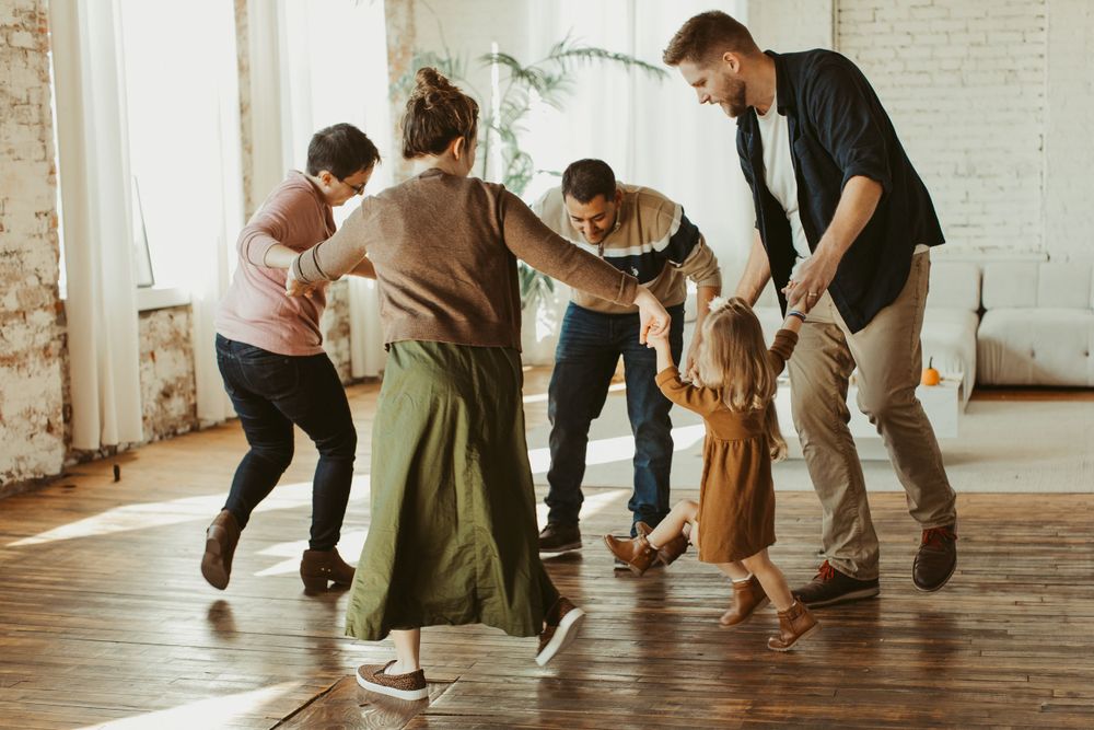 Group of people sitting in a bright white studio space with wooden floors.
