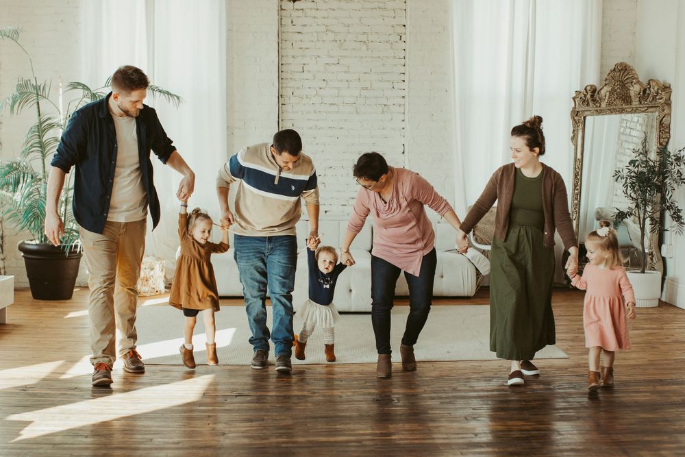 People walking together in a line across a sunlit hardwood floor studio.