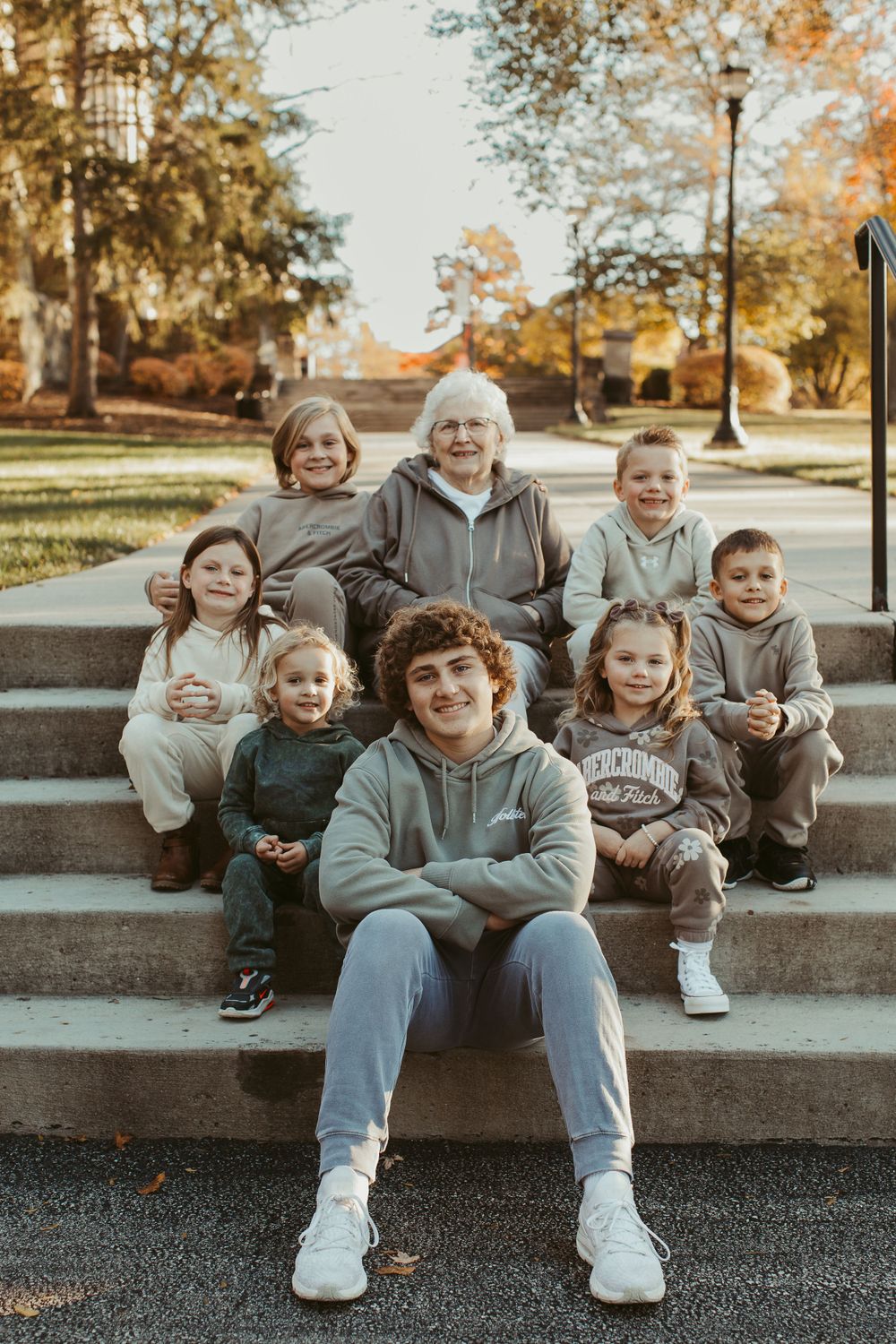 Family members relaxing on concrete steps surrounded by fall foliage.