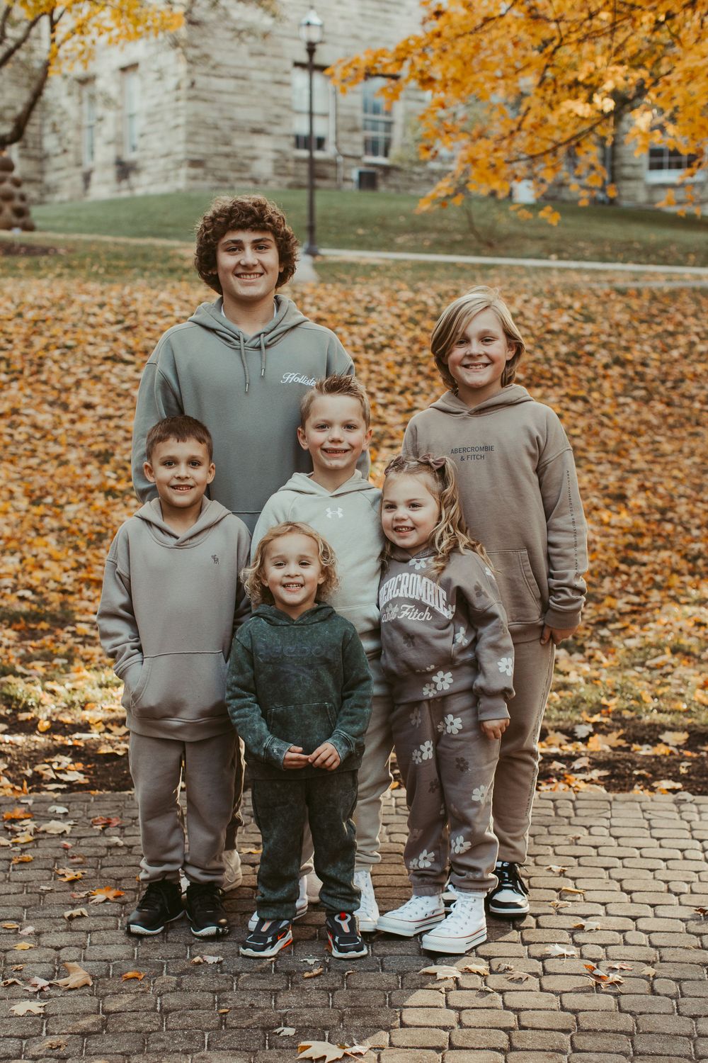 Group portrait on brick pathway with golden autumn leaves scattered around.