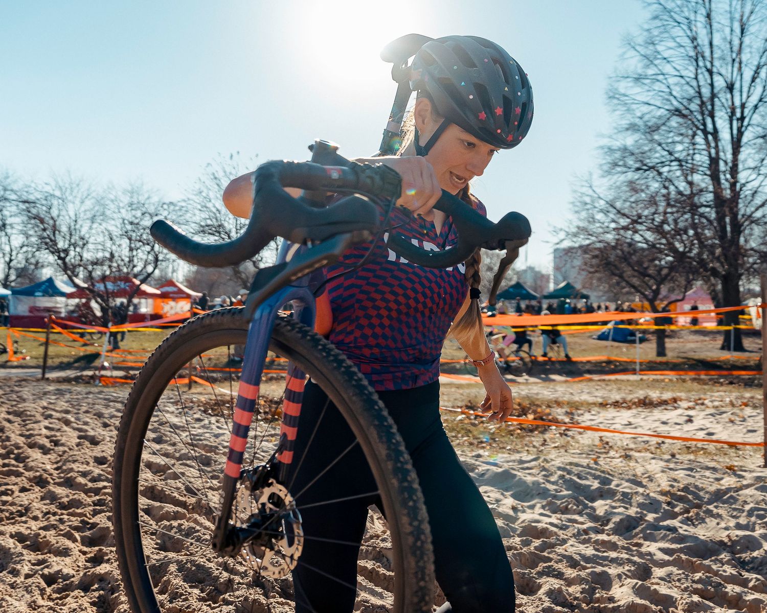 Cyclist navigates a challenging muddy cyclocross race course while dismounting their bike in winter conditions.