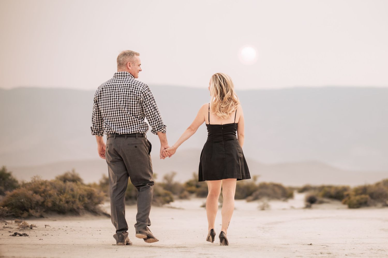 A couple walks hand in hand during a scenic sunset engagement session.