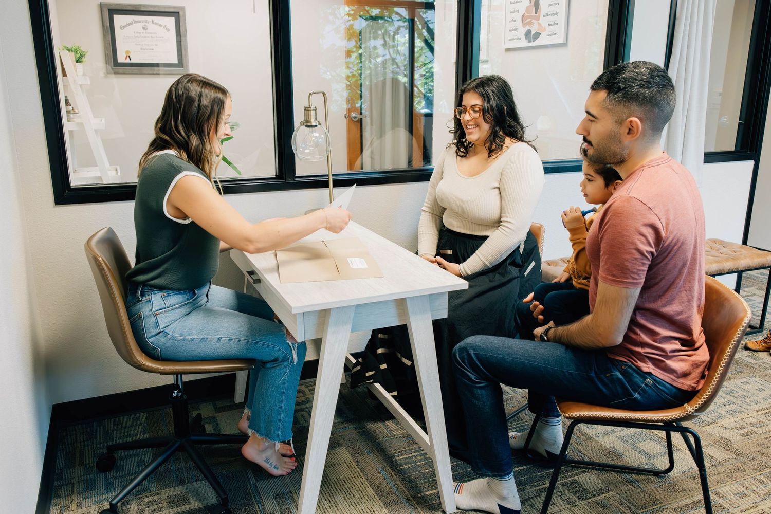 Three people having a consultation meeting around a small white table in a modern office setting.