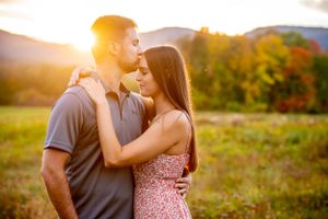 A romantic engagement session in a sunlit field during golden hour.