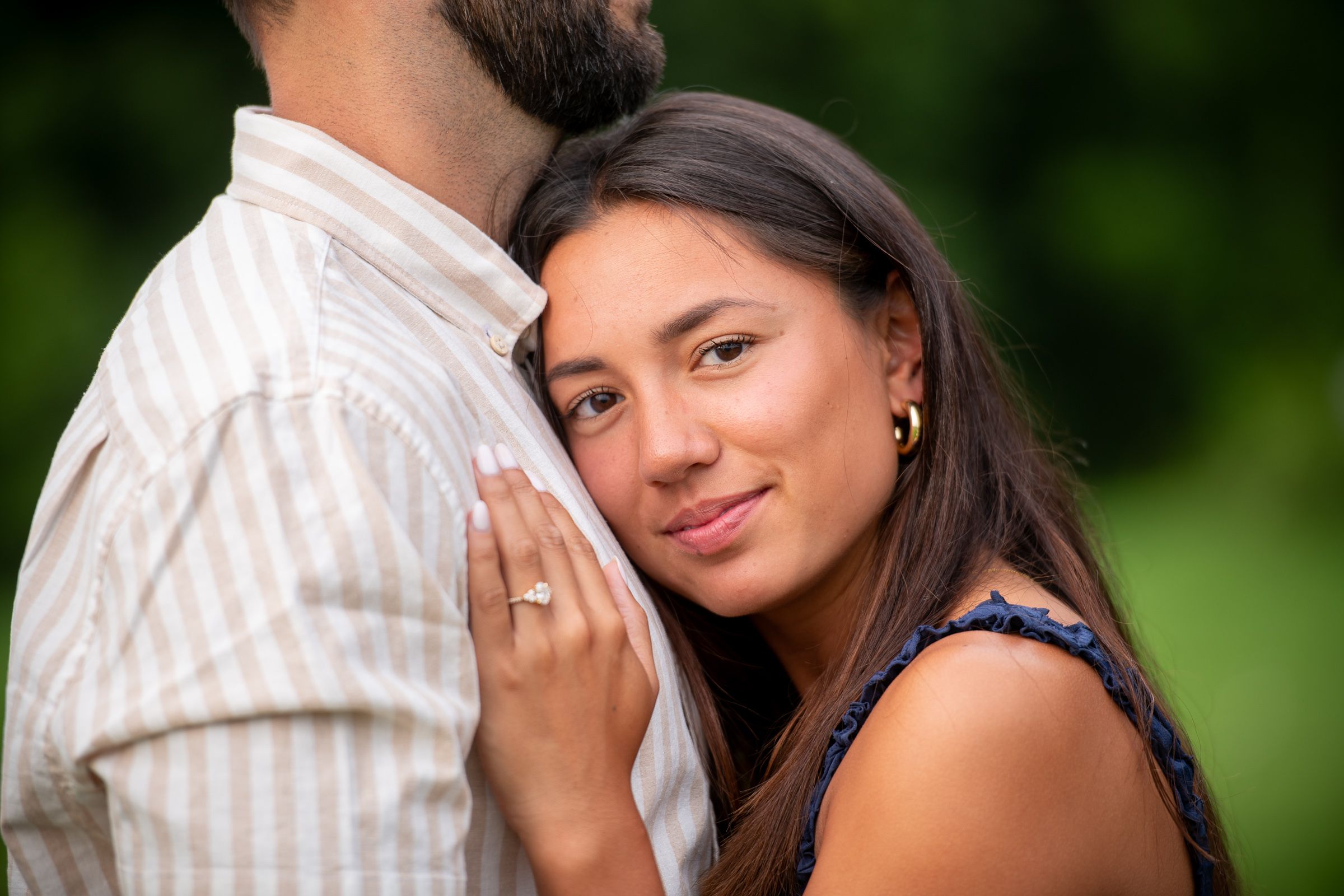 Close up of couple embracing outdoors with natural green background.