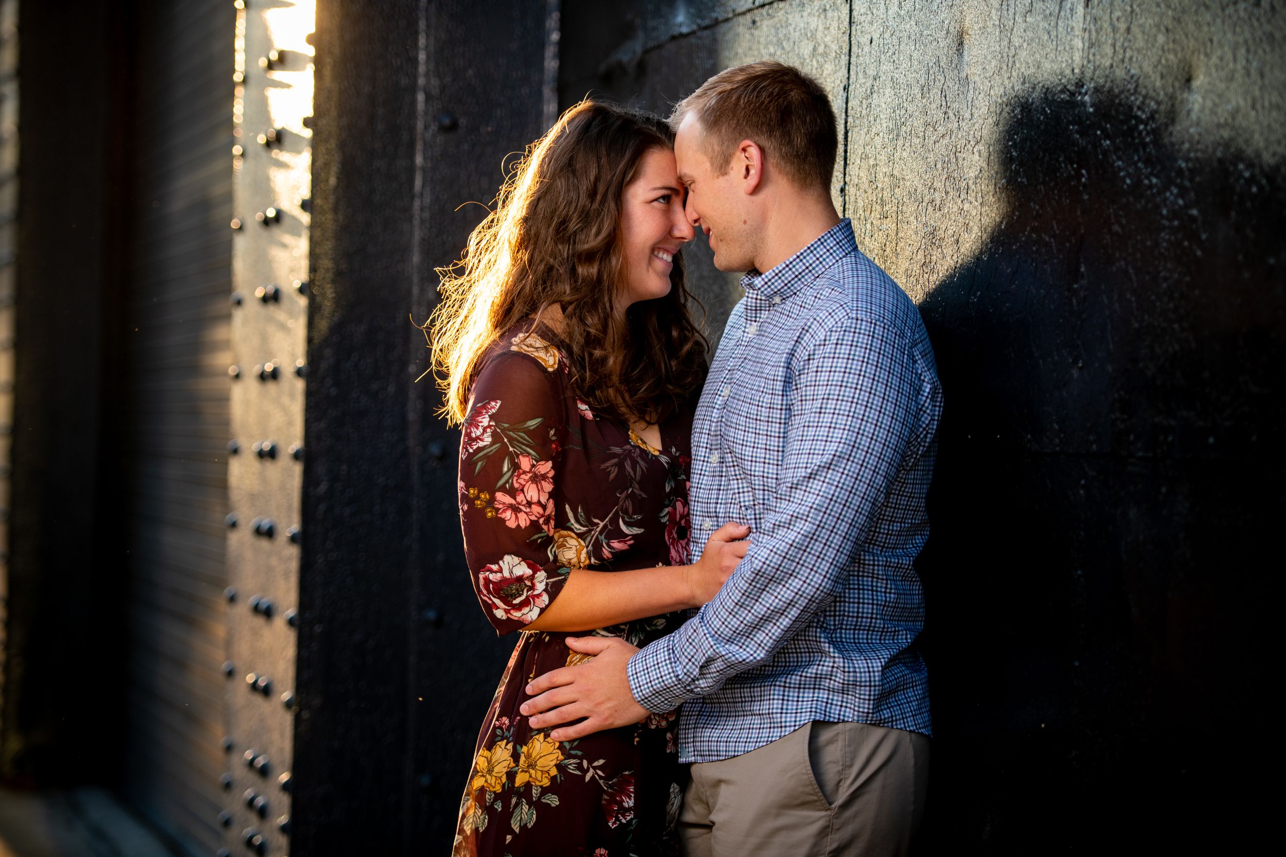 A romantic couple poses together in a charming brick alleyway with dramatic lighting.