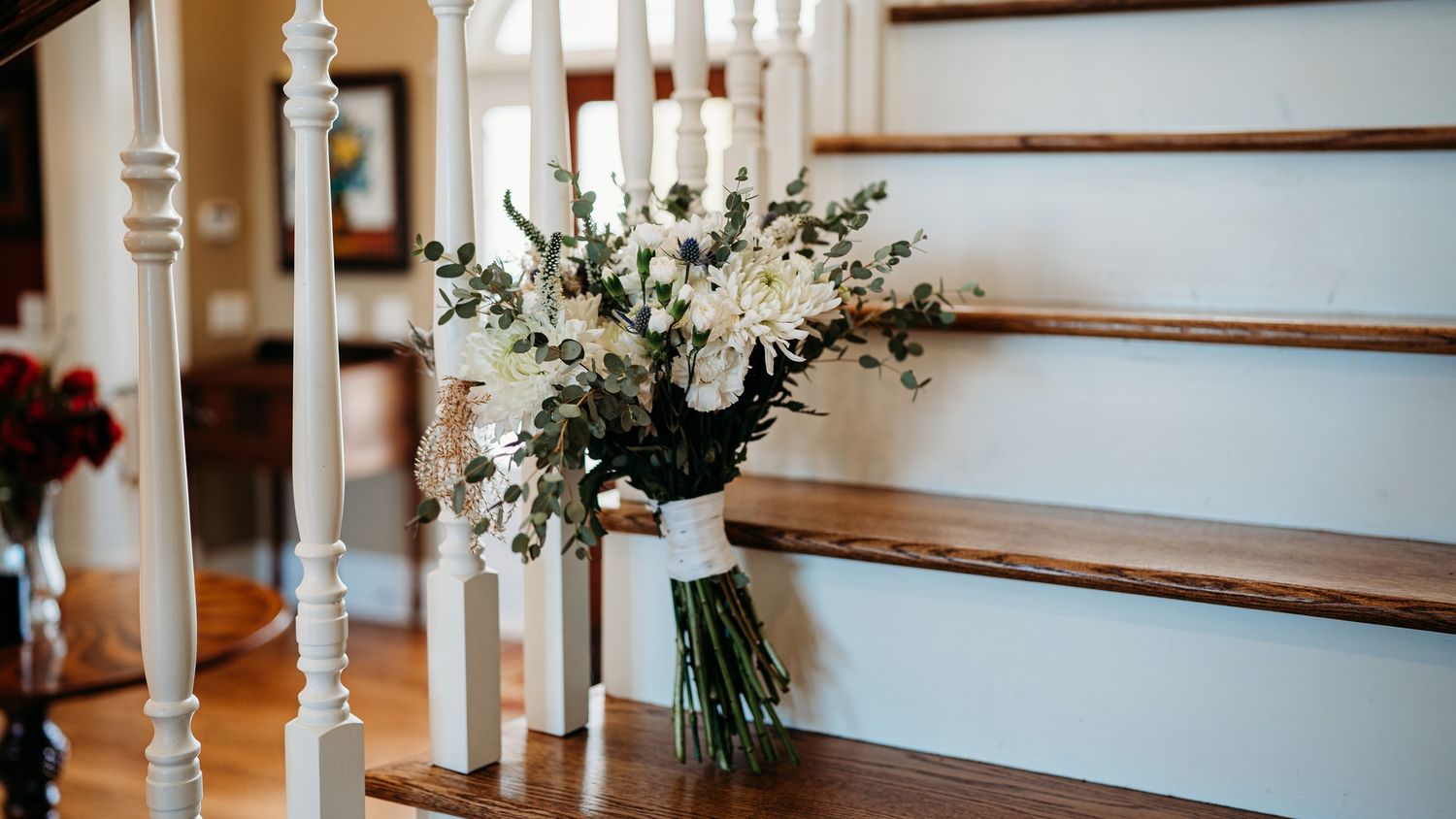 Elegant white floral arrangement with candles on wooden staircase.