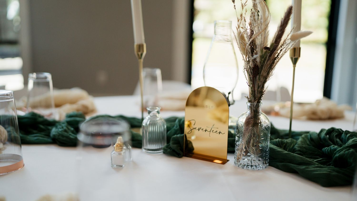 Wedding reception table setting with gold place card and elegant glassware.