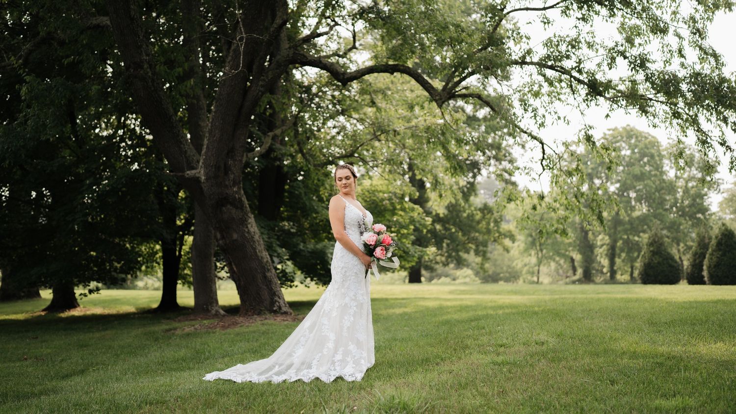 A white wedding dress photographed in a sunlit garden setting.