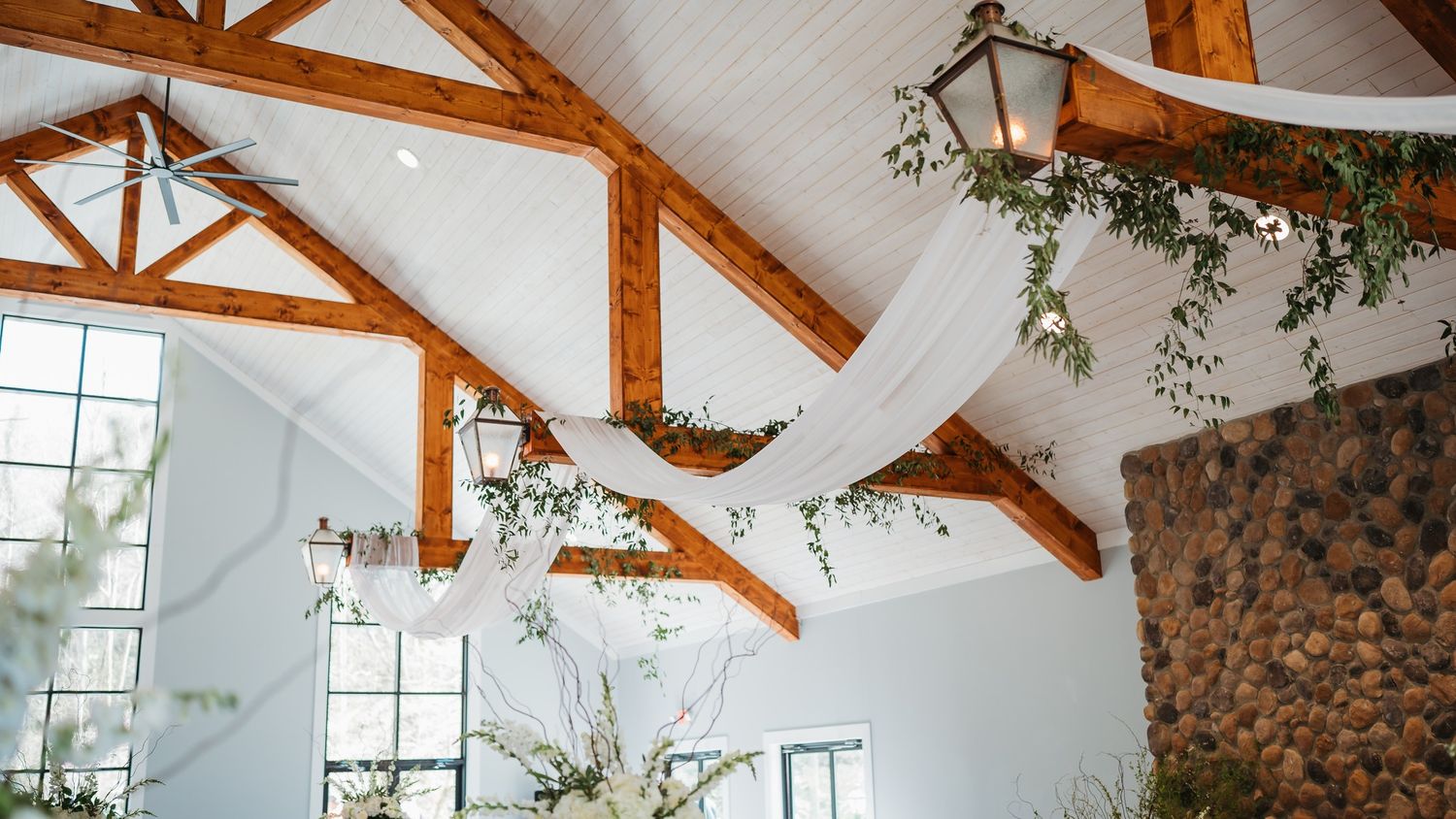 Vaulted ceiling with exposed wooden beams and white walls in a reception venue.