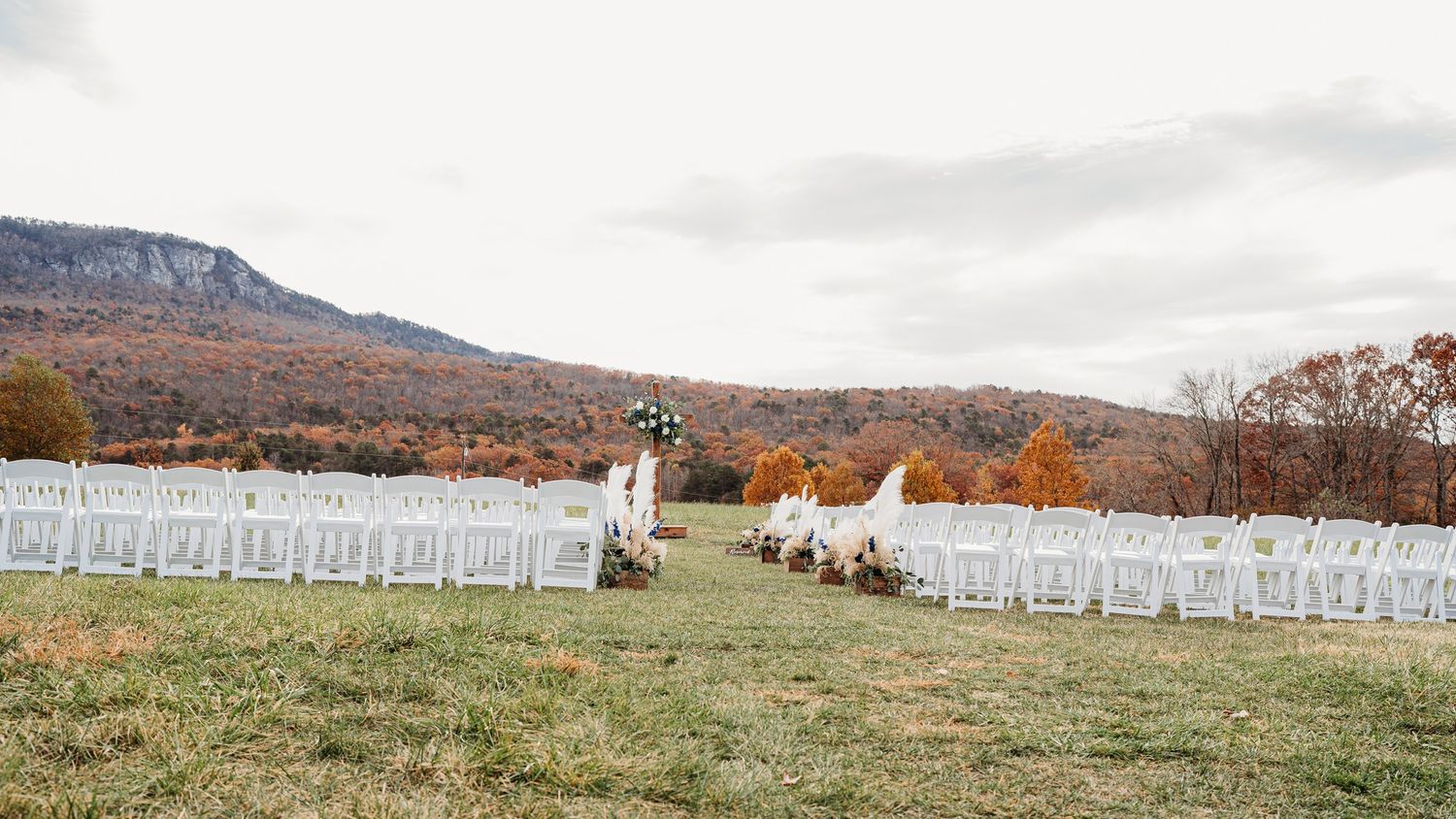 Outdoor wedding ceremony setup overlooking autumn mountains with rows of white chairs.